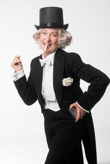 Maureen dressed in a tuxedo and top hat, with a fake cigarette in her mouth