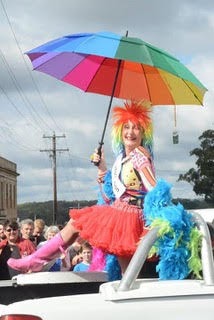 Maureen dressed in rainbow colours brandishing a ranbow umbrella